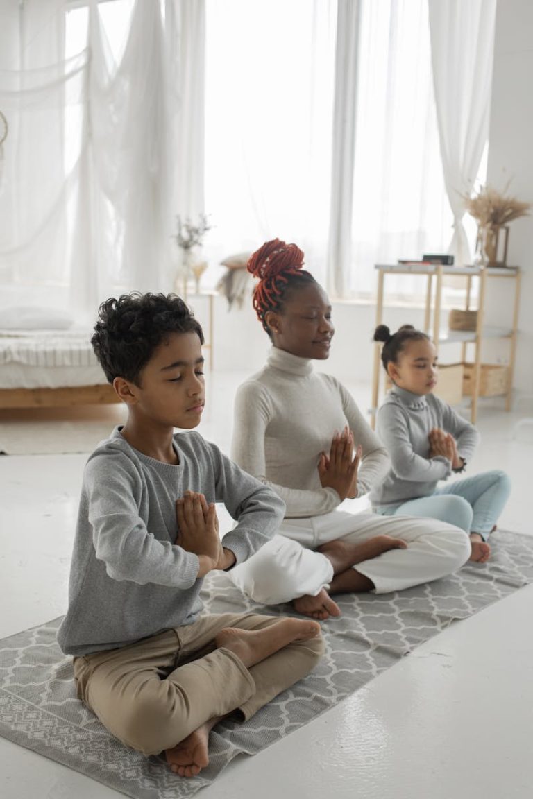 A mother and two children practicing yoga in a serene, well-lit living room.